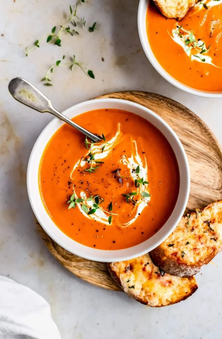 Bowl of roasted butternut squash and red pepper soup topped with herbs