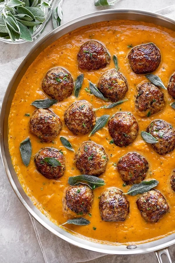 Turkey meatballs served in a creamy pumpkin sage sauce garnished with herbs